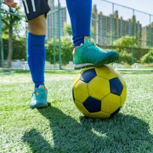 Photo of the legs of a soccer player, with a foot resting on a yellow soccer player